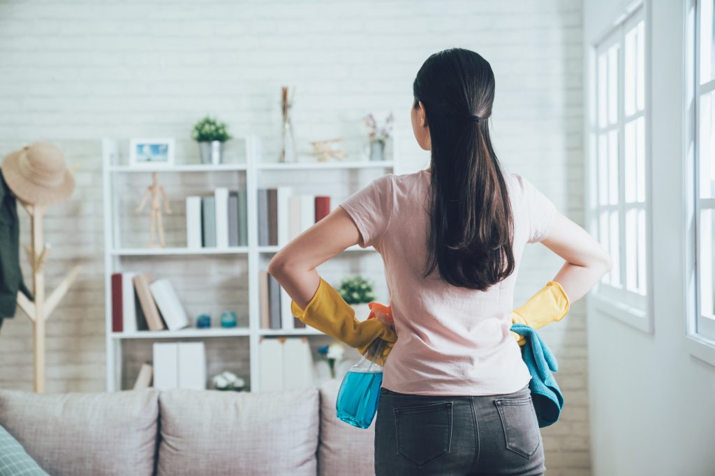 Brunette female with rubber gloves cleaning her living room