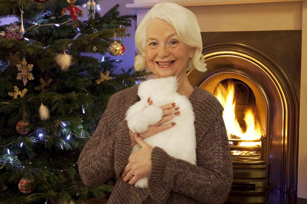 Lady with hot water bottle in front of Christmas tree