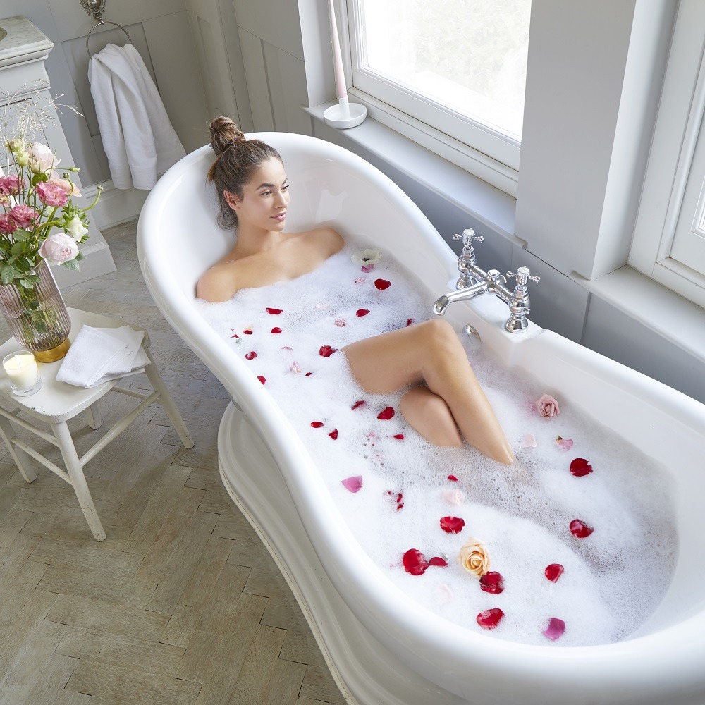 Woman relaxes in a large bubble bath filled with flowers