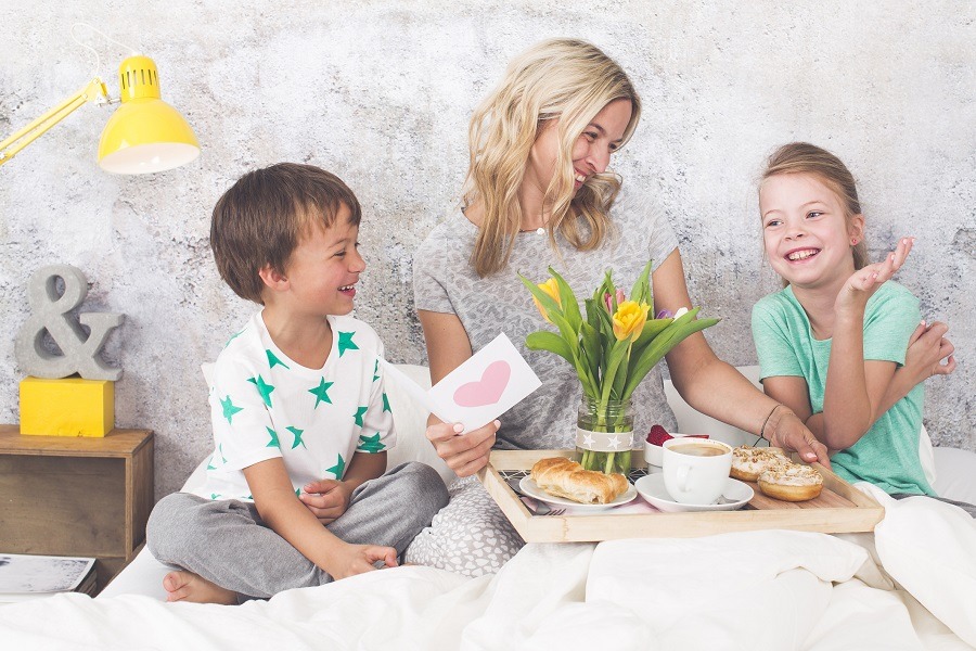 Young son and daughter give their mum breakfast in bed