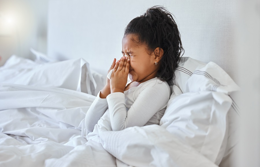 Little girl lies in bed and blows her nose