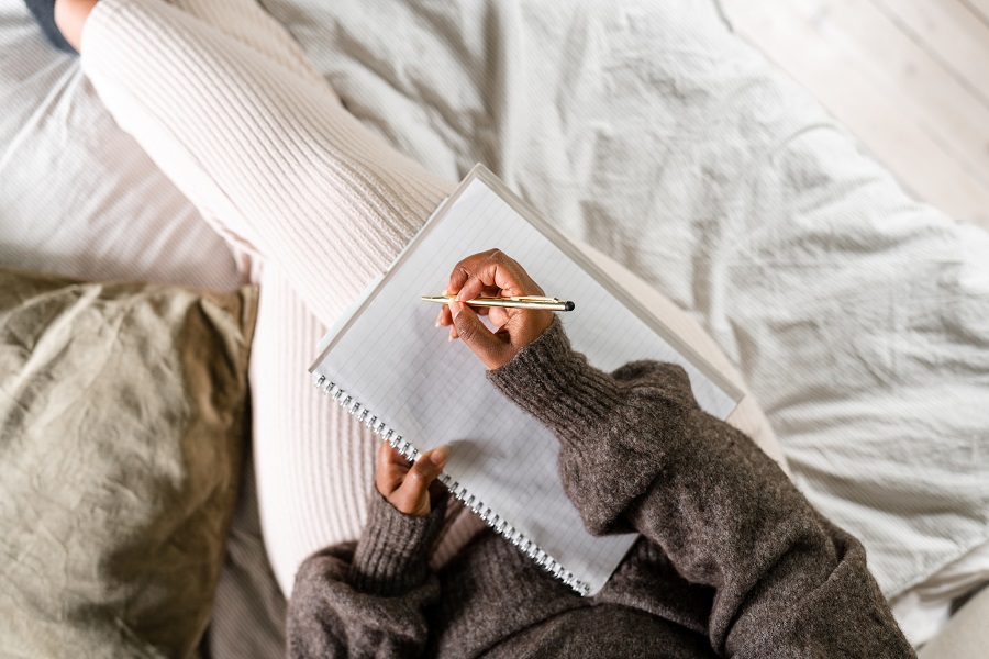 Birdseye view of someone lying on their bed about to write a to-do list