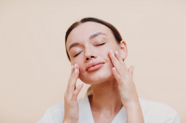 Young woman applying cosmetic white cream on her face