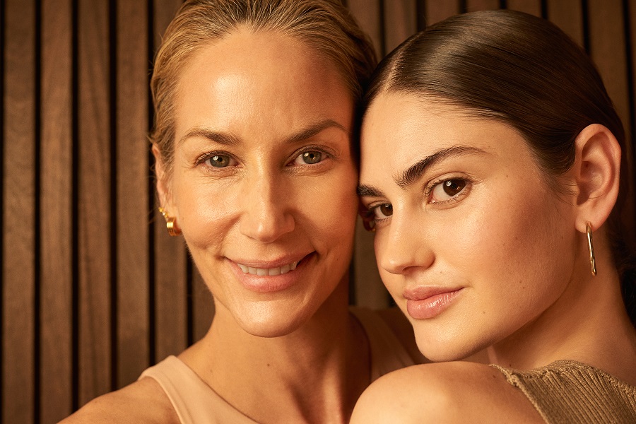 an older and younger woman both smiling into the camera with glowing skin