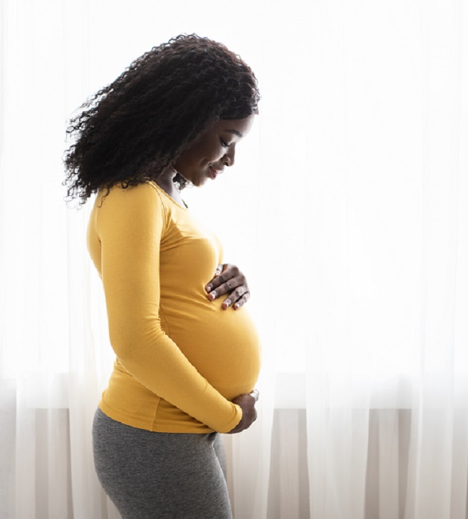 Black pregnant woman holding her belly and smiling 