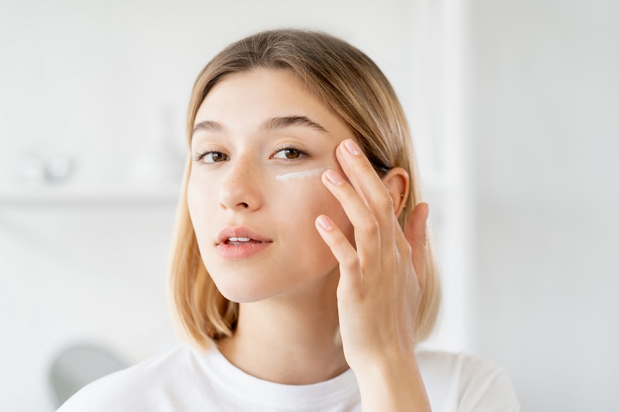 Woman applying primer to face in the mirror