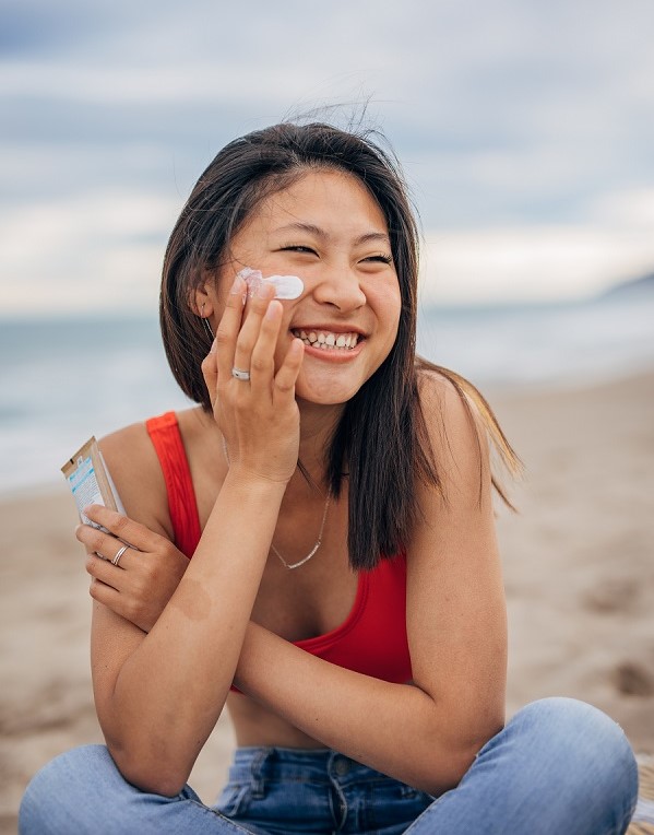 smiling woman applying suncream to face