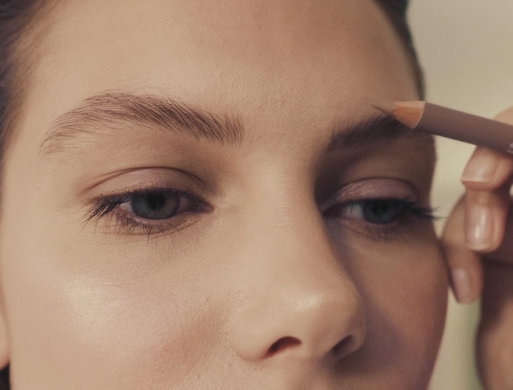 woman applying brow pencil to brows