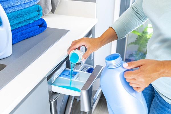 woman adding detergent to washing machine