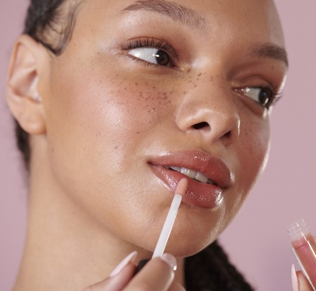 woman applying shiny lipgloss 