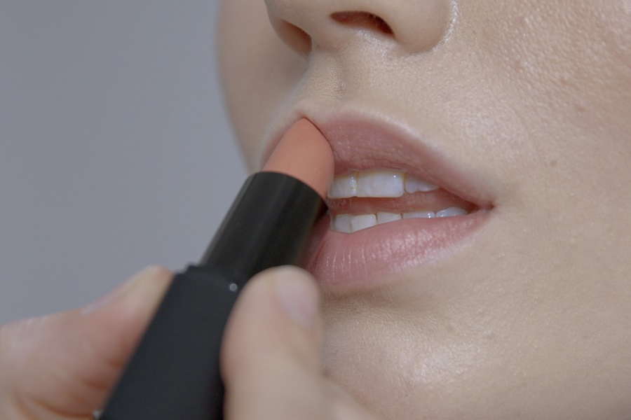 close up of woman applying nude lipstick