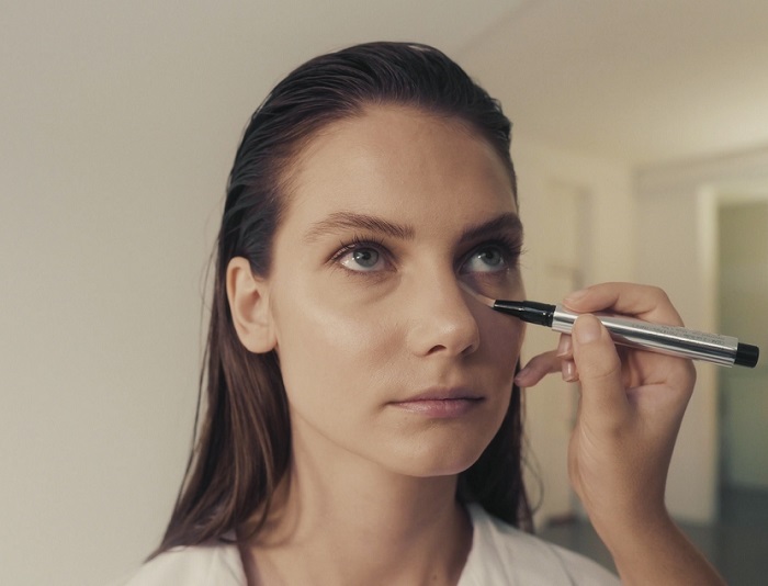 woman applying concealer to under her eyes 