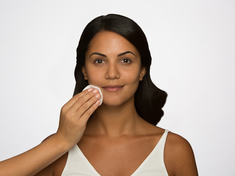 woman cleansing face with wipe 