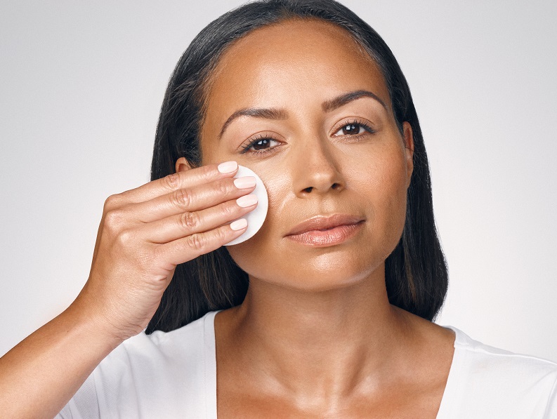 woman applying micellar water to cheeks with a wipe 