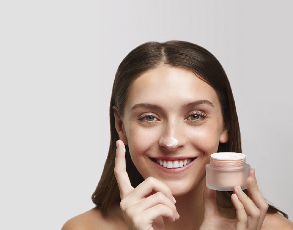 woman smiling applying moisturiser to nose tip 