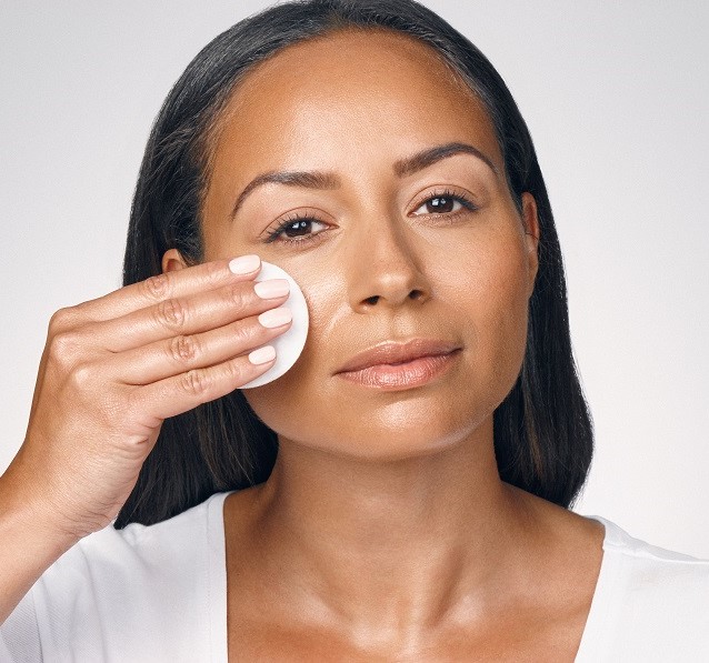 woman applying a cotton pad wiping off make up 